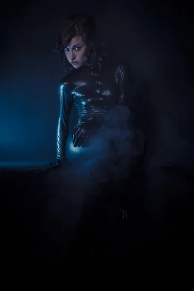 Beautiful brunette woman wearing latex dress on dark background