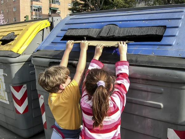Children pulling a cardboard into recycling container for paper