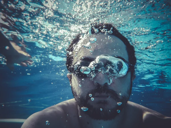 Goggles, man swimming underwater in a pool