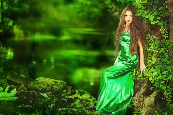Beautiful girl in green dress in fairy forest