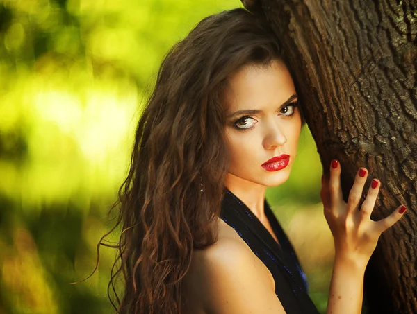 Portrait of beautiful girl in black dress near tree