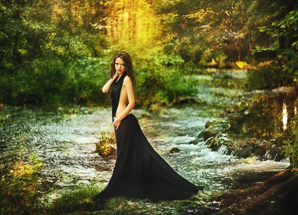 Beautiful girl in black dress in fairy forest