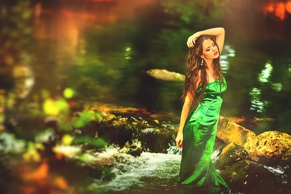 Beautiful girl in green dress in the forest pond