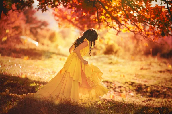 Beautiful girl in a yellow dress walking the air in the forest