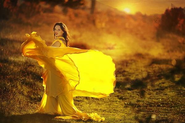 Beautiful girl in a yellow dress walking the air in the forest