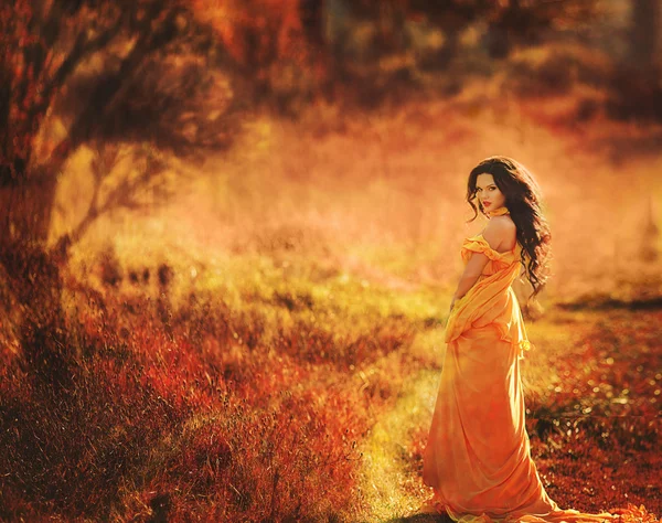 Beautiful girl in a yellow dress walking the air in the forest