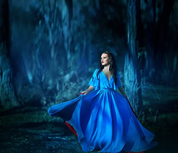 Beautiful girl in blue dress walking in the magical forest