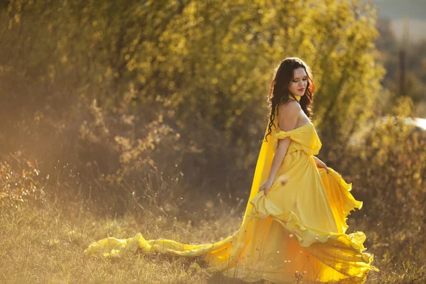 Young beautiful girl in a yellow dress in the woods