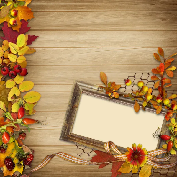 Frame with autumn leaves and berries on a wooden background