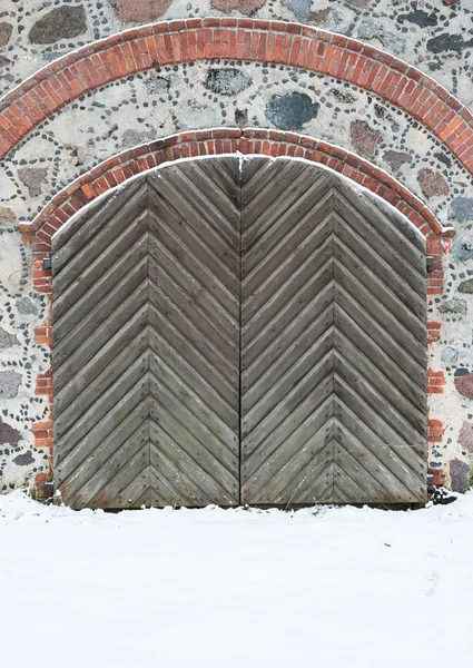 Old wooden gate with pig-iron rivets in a granite wall in the wi