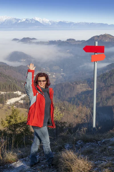 Happy hiker woman at mountain top waving hello