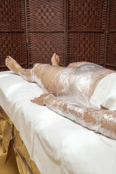 Female body being wrapped around with foil to reduce fat