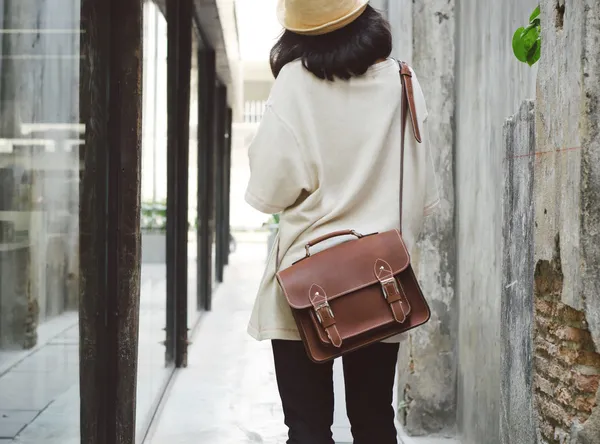 Fashion girl with leather bag at concrete alleyway