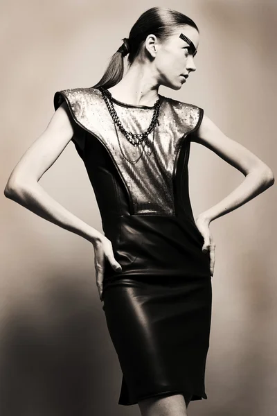 Fashion studio shot of a female model in leather dress looking s