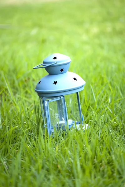 Blue Lantern, with burning candle inside, on green grass