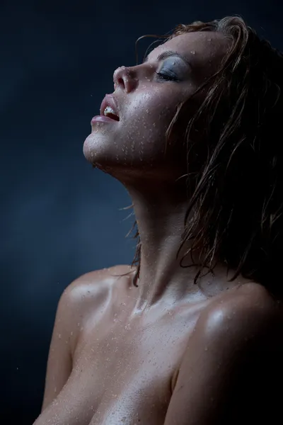 Portrait of a girl's face which water flows on a dark background