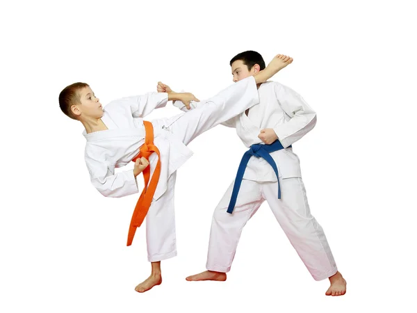 Two athletes with orange and blue belts are doing paired karate exercises