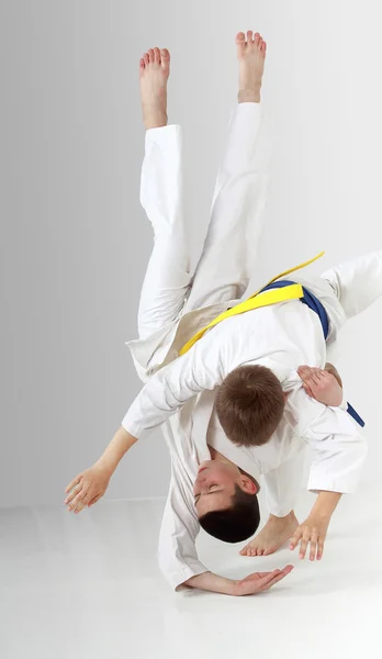 Boy with a blue belt throws boy with yellow belt