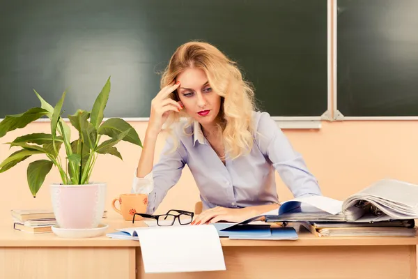 Tired teacher checking the tests.