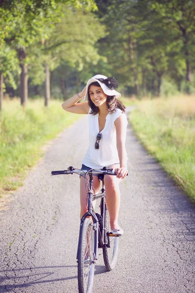 Smiling young woman biking on a country road