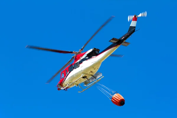 Emergency helicopter extinguishes flames of a raging bush fire