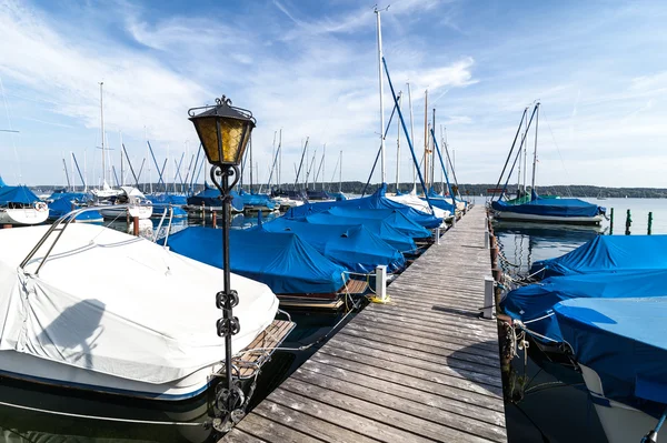 Covered boats and yachts docked at wooden pier