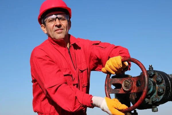 Smiling Oil Worker Turning Valve On Oil Rig