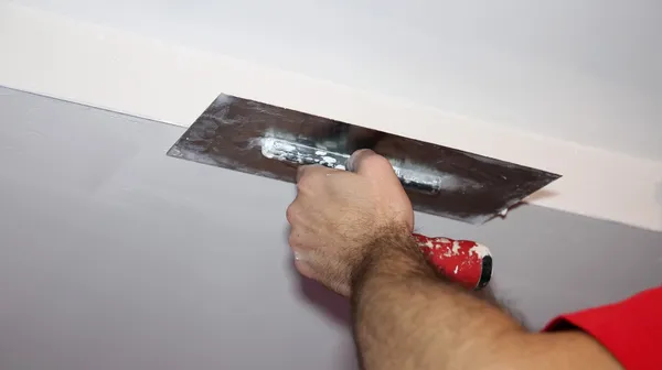 Construction Worker Plastering Ceiling With Work Tool