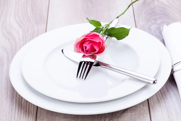 Table setting with a single pink rose