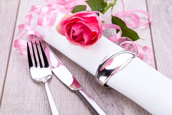 Table setting with a single pink rose