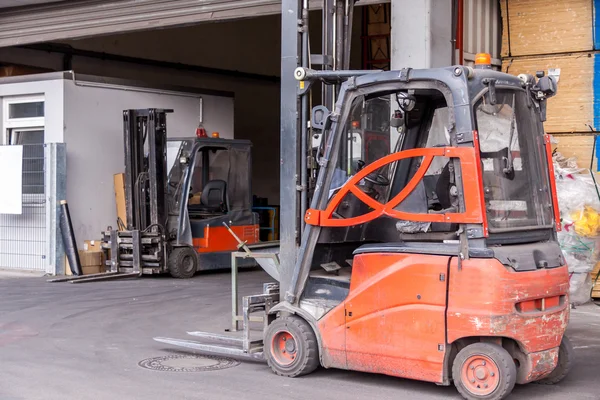 Small orange forklift parked at a warehouse
