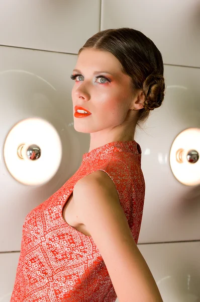 Portrait of a orange dressed girl with lamp bulbs behind