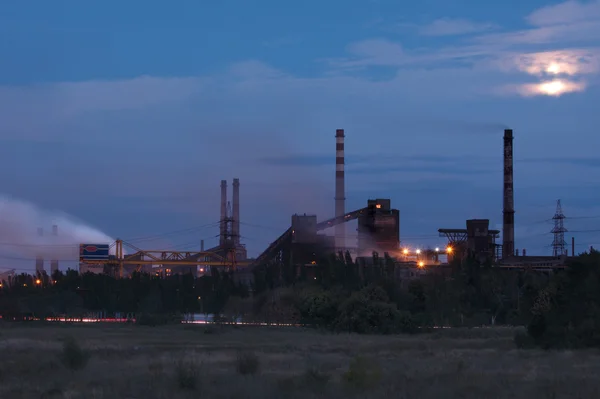 Metallurgical factory with smoke stack at night
