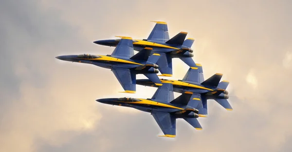 Blue Angels flying in tight diamond formation at a public airshow.