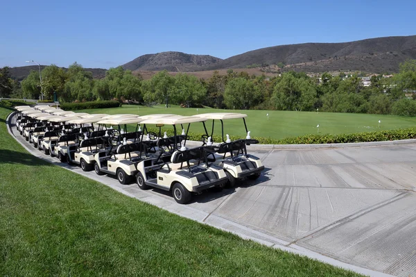 Line of golf carts - several pairs of carts waiting for a game of golf on a clear blue sunny day in Southern California.