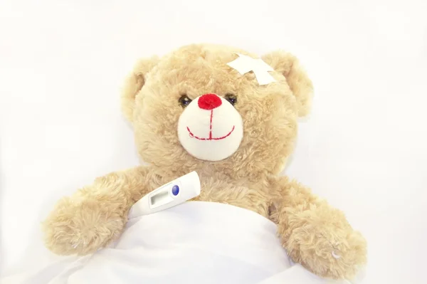 Teddy bear with a thermometer isolated on white background