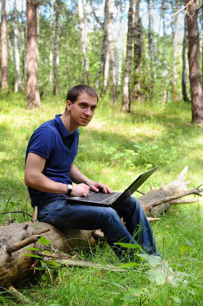 Young man with laptop in the forest