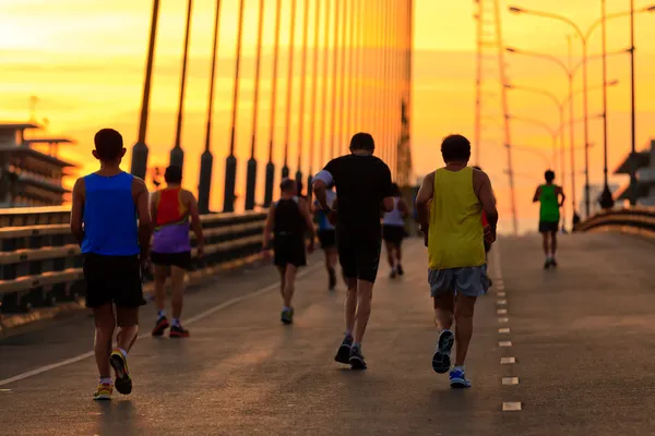 Stock Photo: Runners run on bridge in morning