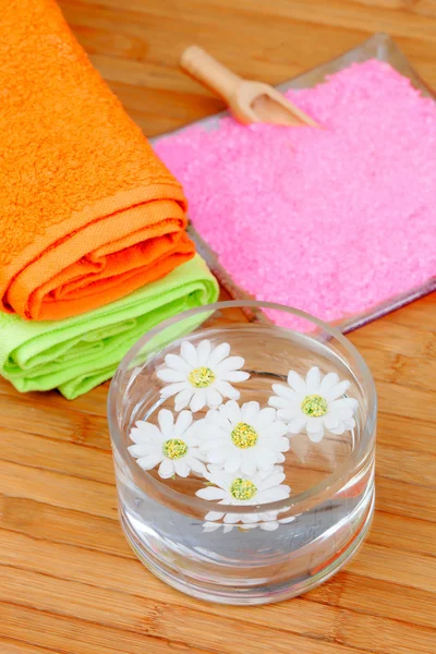 Two colorful towels next to a bowl of water with flowers
