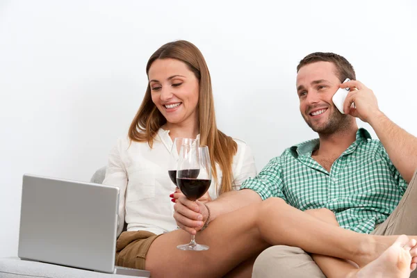 Couple relaxing with glass of wine on couch.