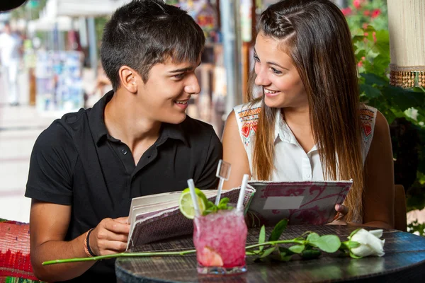 Young couple with restaurant menu at table.