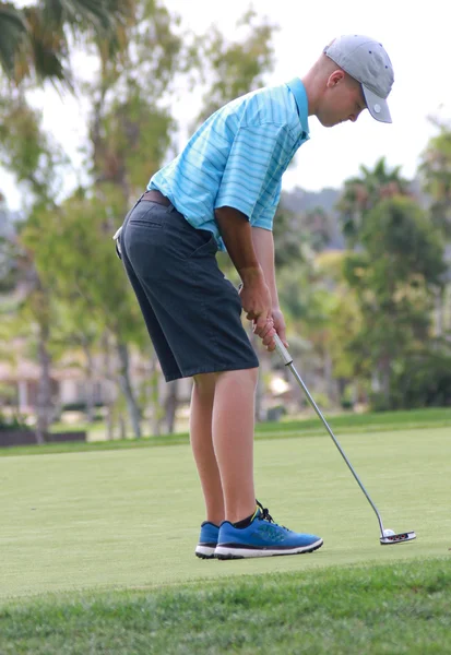 Male teen golfer preparing to putt