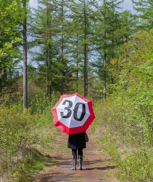 Woman in the forrest with a traffic sign umbrella