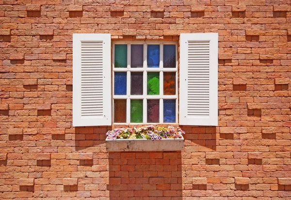 White window with flower pots on the brick wall.