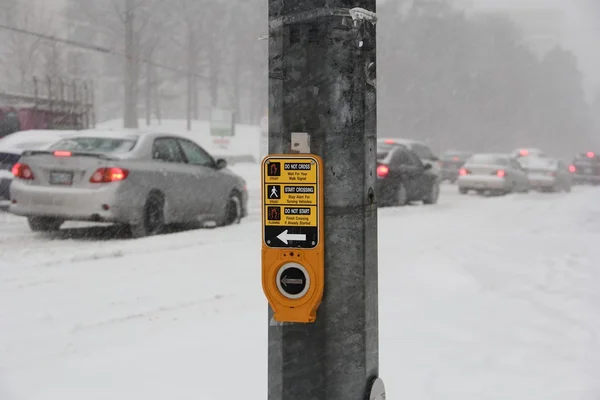 Pedestrian traffic stop button close up with snow storm on the background