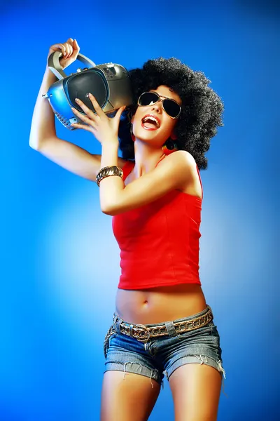 Happy tanned woman with afro haircut enjoying music holding tape recorder.
