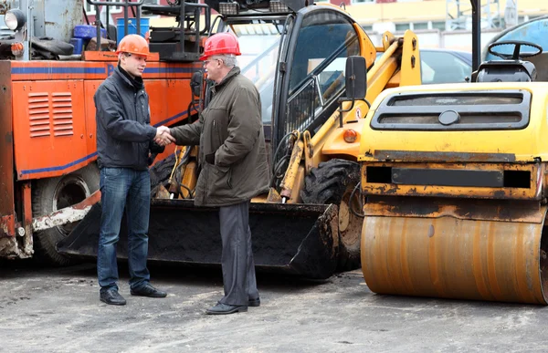 Two managers of the works in hard hats shaking hands