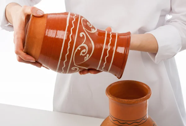 Cook pouring something into clay jug
