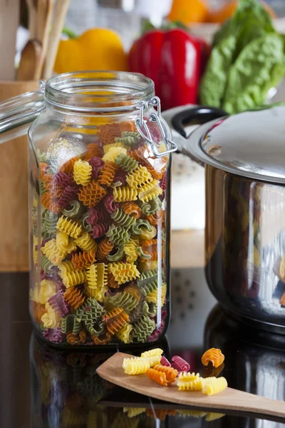 Large Storage Jar with Colorful Pasta and Cooking Spoon