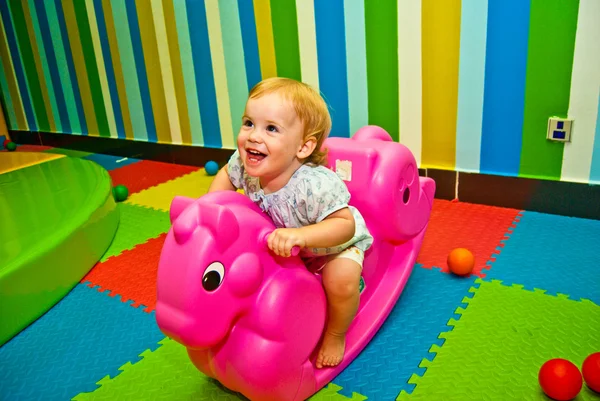 Girl 1,5 year old swinging on a pink rocking horse